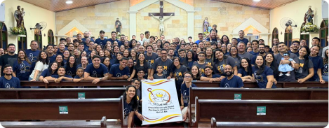 Comunidade do Segue-me reunida na igreja com a bandeira do movimento